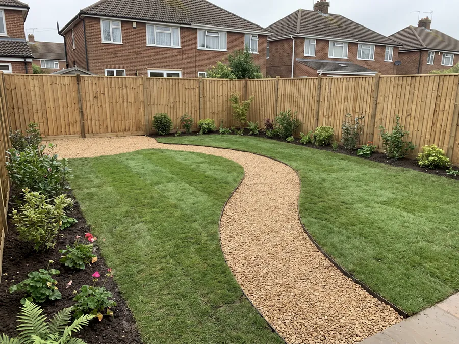 Rebuilt rear garden with a curved gravel path, shaped lawn and freshly planted borders behind a new close-board fence