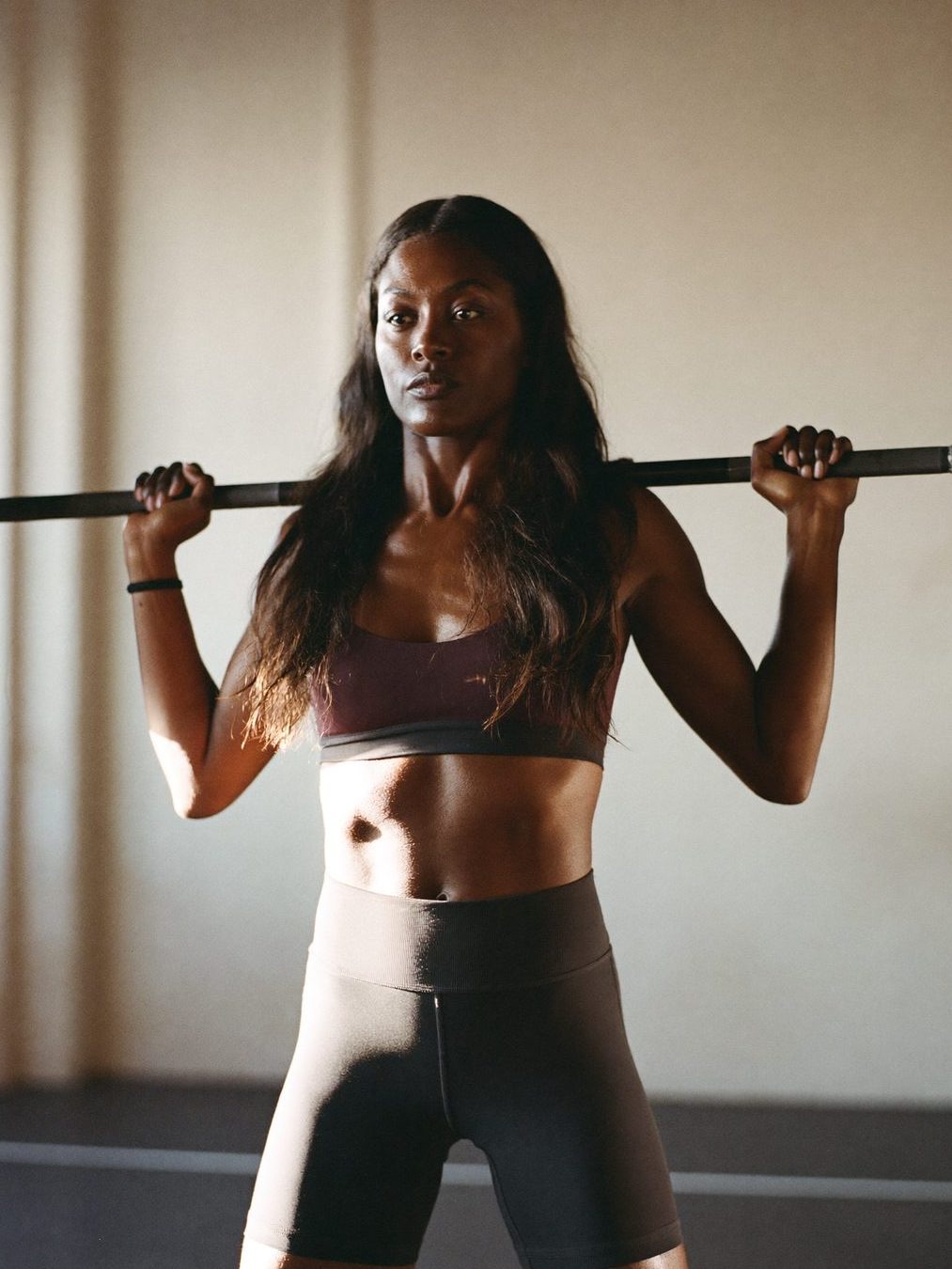 A woman performing a controlled barbell deadlift with good form